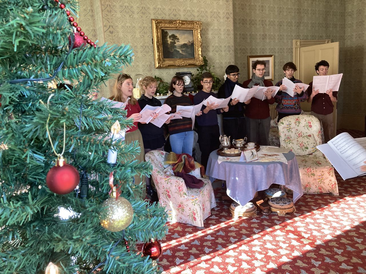 A choir signing with a Christmas tree