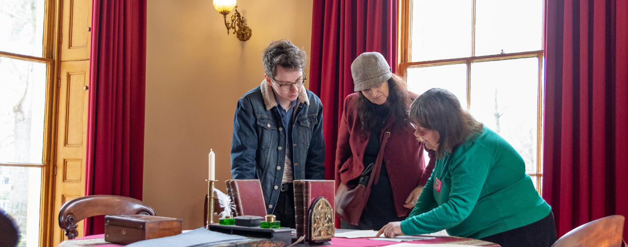 2 visitors engaging with a volunteer in a Victorian setting
