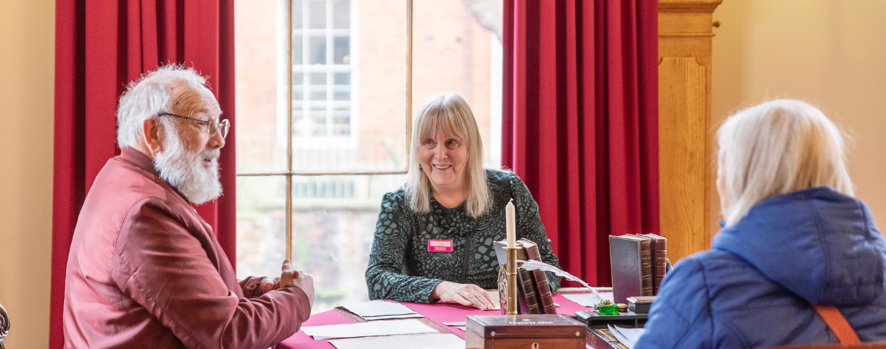 Three people sat around a table talking.