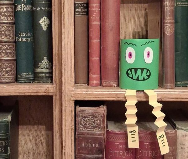 A hand crafted monster on a shelf of old books