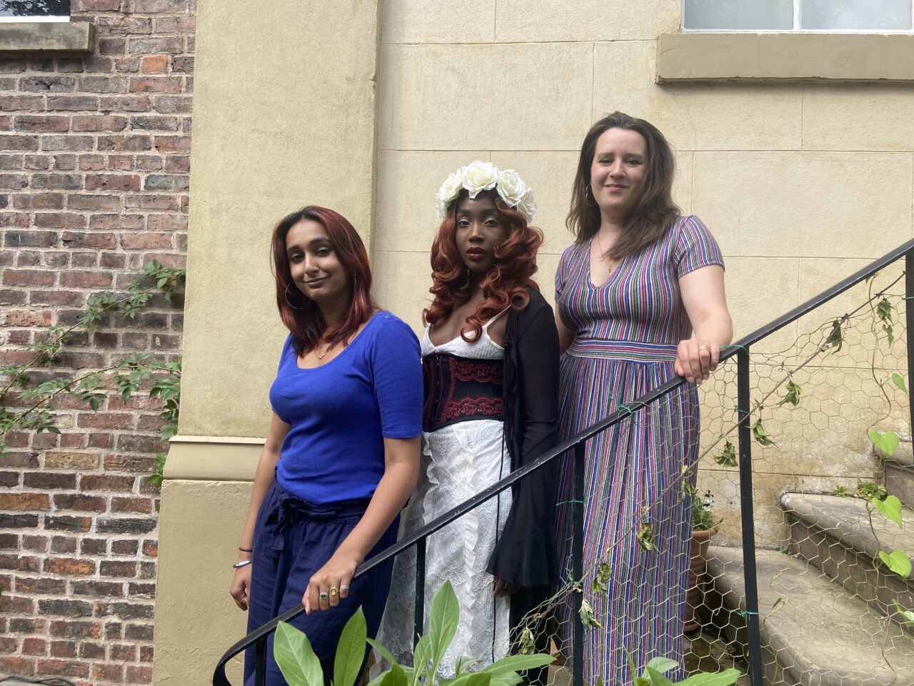 Three women writers stood on steps outside Elizabeth Gaskell's House.